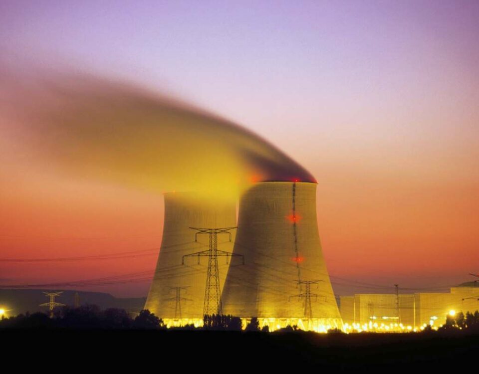 Nuclear power plant cooling towers emit steam at dusk.
