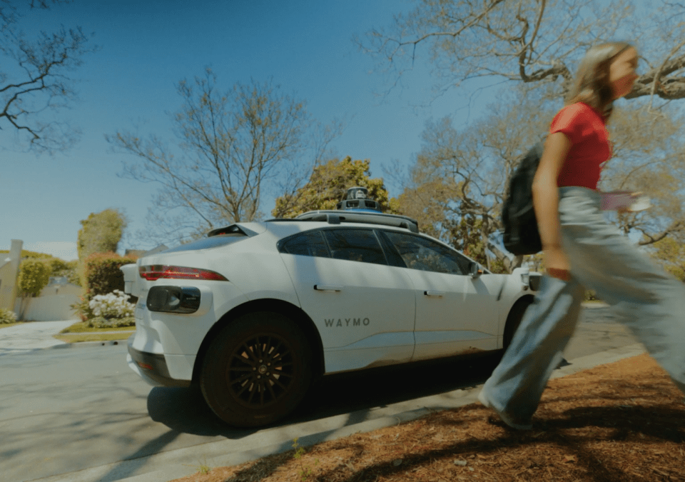 A Waymo robotaxi on the street in Phoenix and a teenage girl walking away from it.