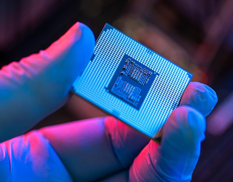 A gloved hand holds a computer chip.