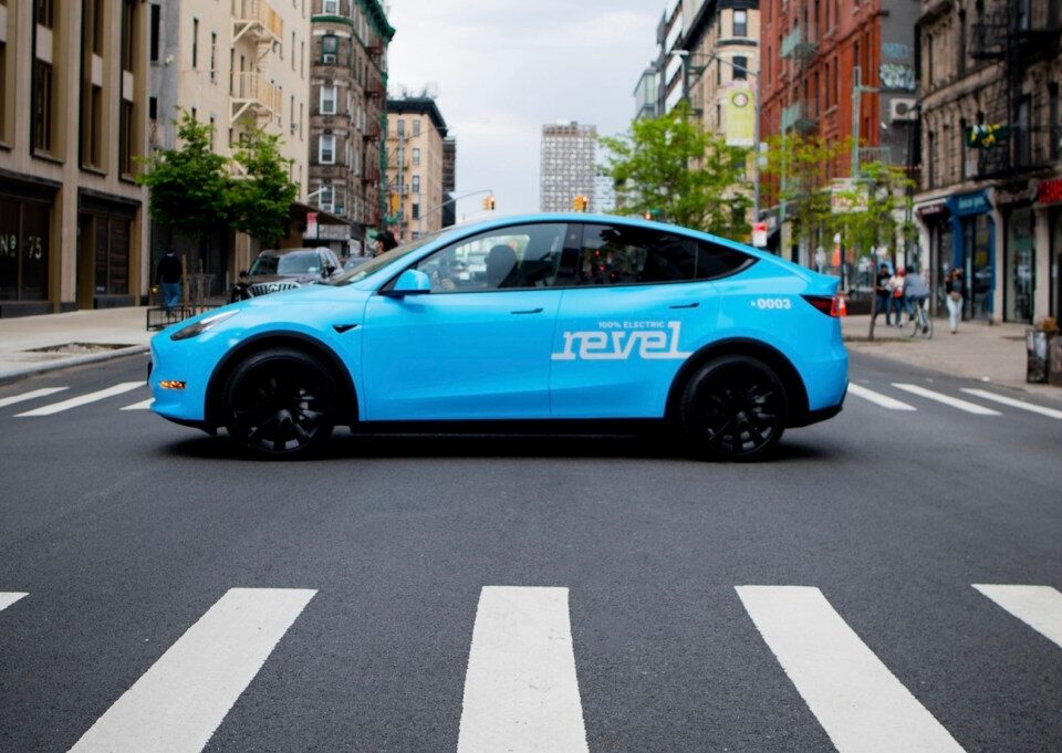 Light blue Revel rideshare mid-street