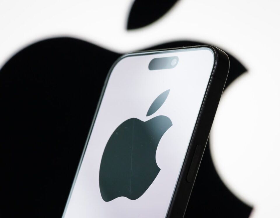 In this photo illustration, the logo of Apple Inc. is displayed on a smartphone screen, with the company's iconic black apple symbol visible in the background.
