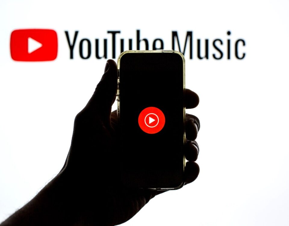 The YouTube Music app seen displayed on a smartphone screen and a YouTube Music logo in the background.