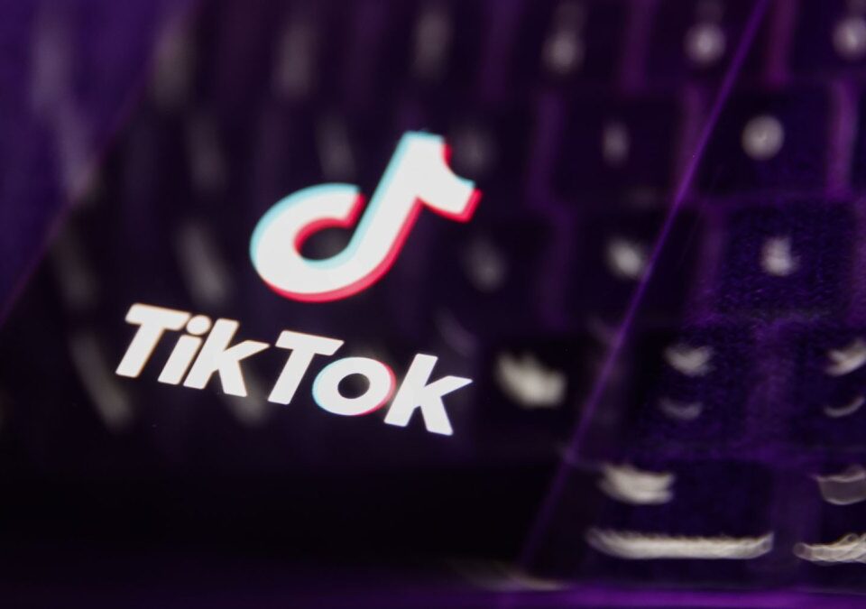A laptop keyboard and TikTok logo displayed on a phone screen are seen in this multiple exposure illustration.