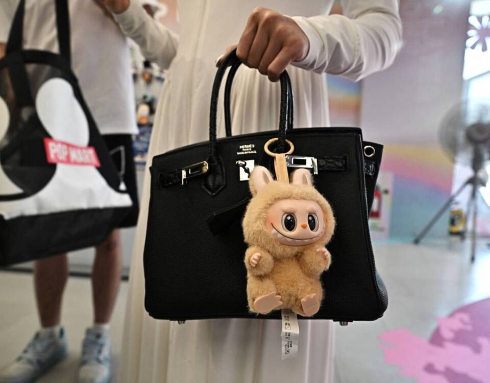 designer art toy Labubu attached to a shopper's handbag at the Pop Mart store in Siam Square in Bangkok. (