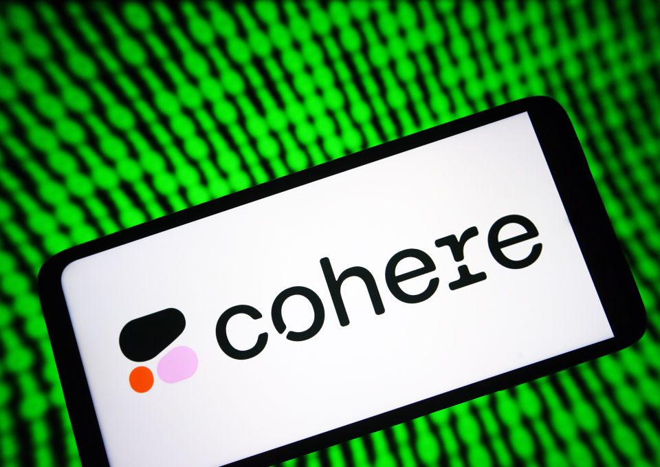 Image of a phone with Cohere's logo on it with a green digital background.
