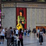 People walk past a Gucci store with a large advertisement displayed on its exterior at the Jiefangbei central business district on September 9, 2025, in Chongqing, China.