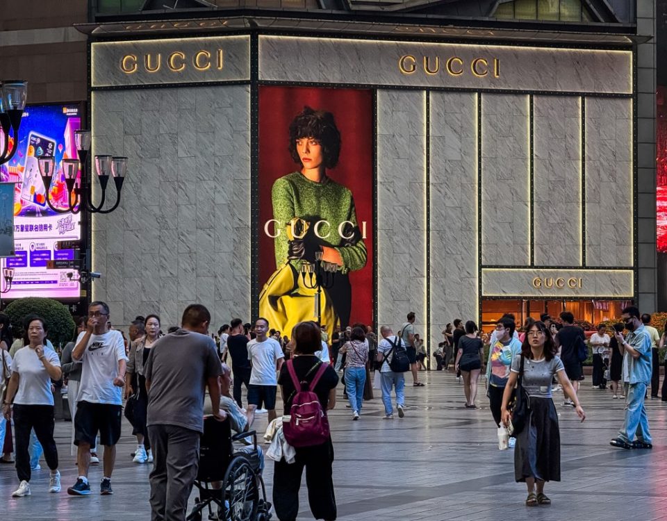People walk past a Gucci store with a large advertisement displayed on its exterior at the Jiefangbei central business district on September 9, 2025, in Chongqing, China.