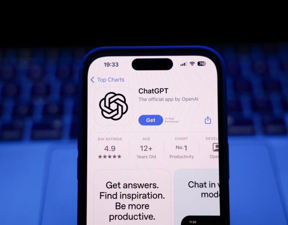 A laptop keyboard and ChatGPT on App Store displayed on a phone screen.