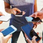 5 friends with smartphones, close up.