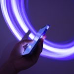 someone holding a phone on a neon purple background
