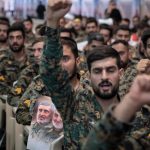Military members of the Iranian police special forces shout anti-U.S. and anti-Israeli slogans as one of them holds a poster featuring portraits of the former commander of the Islamic Revolutionary Guard Corps Quds Force, Major General Qassem Soleimani, who is killed in a U.S. strike in Baghdad, and Brigadier-General Amir Ali Hajizadeh, former Commander of the IRGC - Aerospace Force, during a ceremony at the Imam Khomeini Grand Mosque in Tehran, Iran, on August 7, 2025, to commemorate the civilians and Islamic Revolutionary Guard Corps (IRGC) generals killed during the 12-day war between Iran and Israel.