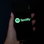 Hand holding a mobile phone with the logo of Spotify on its screen.