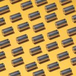 A large group of batteries laid in a pattern on a yellow background