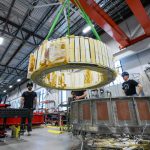 Engineers watch as a magnet is moved inside Commonwealth Fusion System's building.