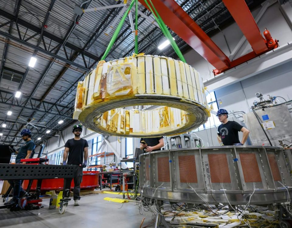 Engineers watch as a magnet is moved inside Commonwealth Fusion System's building.