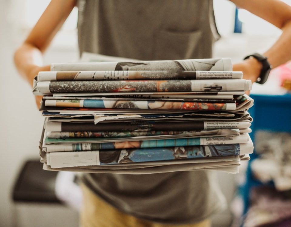 A person holding a pile of newspapers.