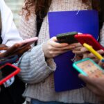 Close up of young college students hands holding mobile phones.