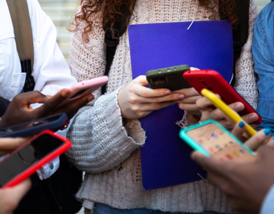 Close up of young college students hands holding mobile phones.