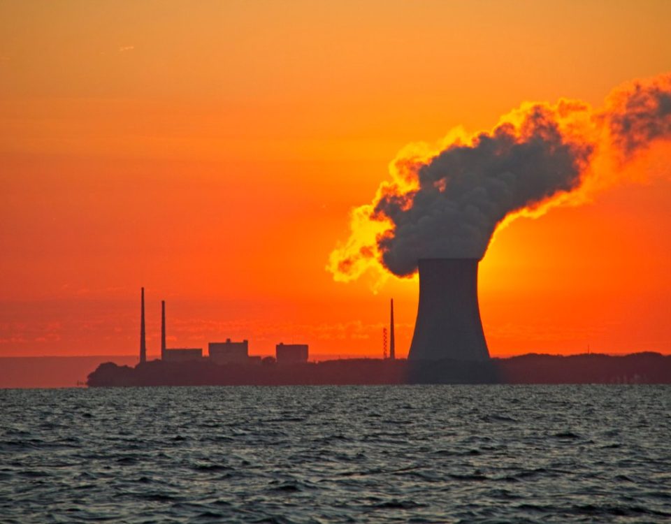 The sun rises behind a nuclear power plant cooling tower.