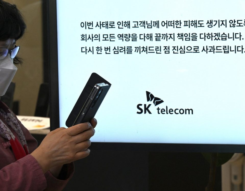 A woman uses her mobile phone while waiting to replace her USIM ship in front of an SK Telecom branch in Seoul on April 28, 2025.