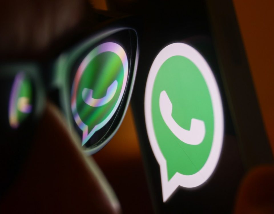 WhatsApp logo reflected on sunglasses and displayed on a phone screen.