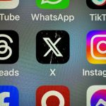 In this photo illustration the logo of US online social media and social networking site 'X' (formerly known as Twitter) is displayed centrally on a smartphone screen alongside that of Threads and Instagram
