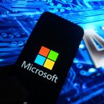 Image of a smart phone with the Microsoft logo on it with "AI" in the background, Nscale