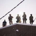 U.S. Immigration and Customs Enforcement (ICE) agents, Department of Homeland Security (DHS) personnel, and Border Patrol Commander Gregory Bovino stand together amidst a tense protest outside the ICE processing facility in Broadview, Illinois, on September 27, 2025.