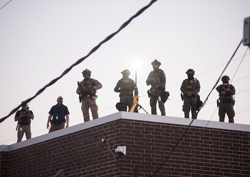 U.S. Immigration and Customs Enforcement (ICE) agents, Department of Homeland Security (DHS) personnel, and Border Patrol Commander Gregory Bovino stand together amidst a tense protest outside the ICE processing facility in Broadview, Illinois, on September 27, 2025.