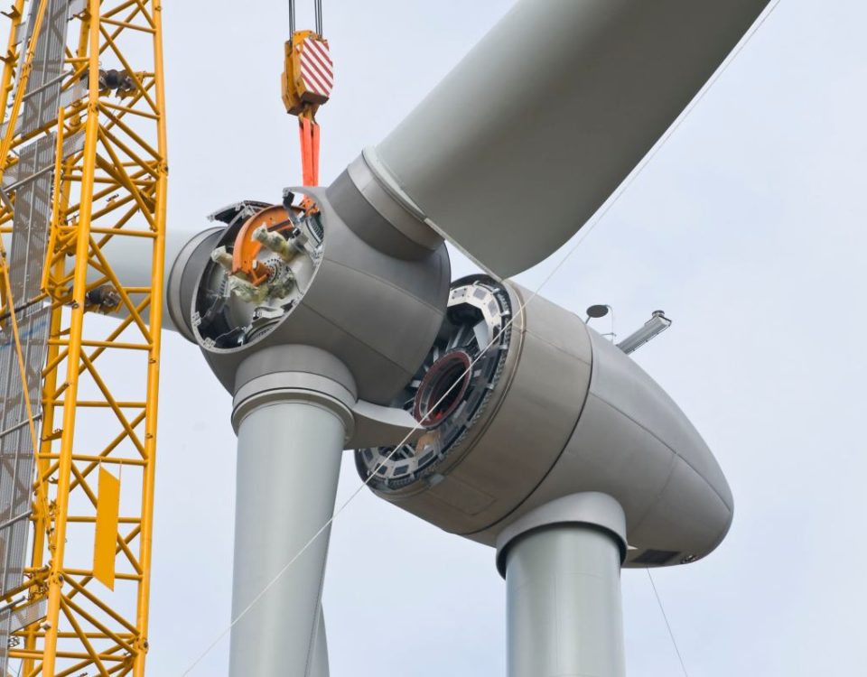 A crane positions the rotor of a wind turbine during construction.