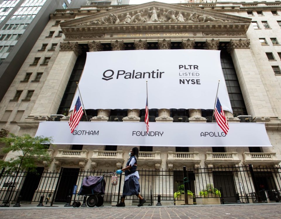 A mail carrier wearing a protective mask passes a banner displaying Palantir Technologies Inc. signage during the company's initial public offering (IPO) in front of the New York Stock Exchange (NYSE) in New York, U.S., on Wednesday, Sept. 30, 2020.