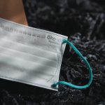 A white surgical mask sits on a black rock.