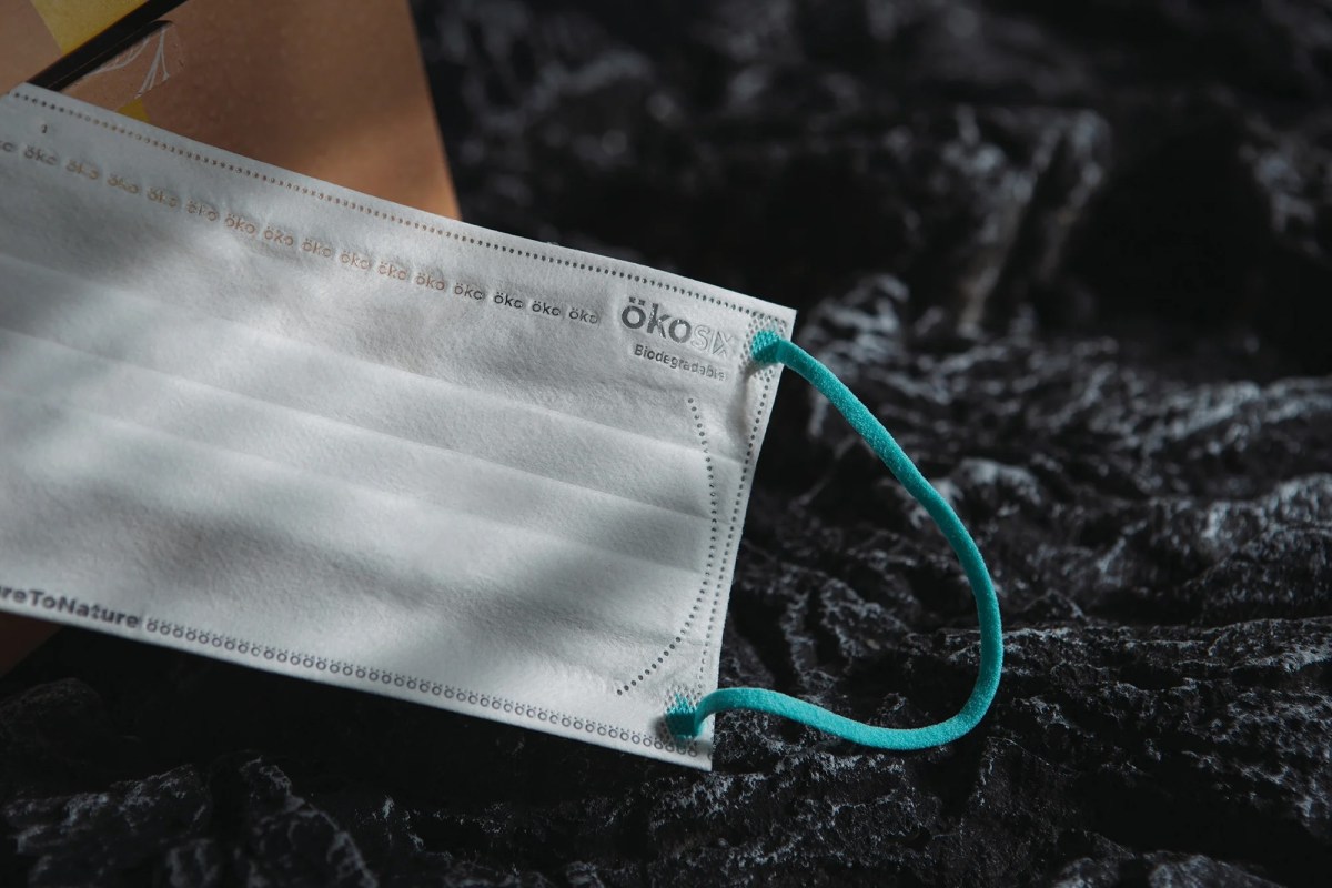 A white surgical mask sits on a black rock.