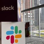 Cubes with Slack name and logo stacked on one another with city view in background.