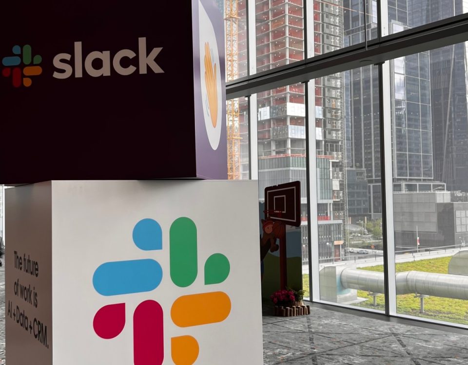 Cubes with Slack name and logo stacked on one another with city view in background.