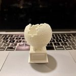 A 3D-printed version of the Wikipedia logo rests on the touchpad of an open MacBook.