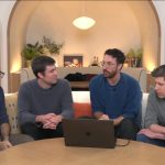 Four OpenAI employees wearing crewneck sweaters sit around a café table.