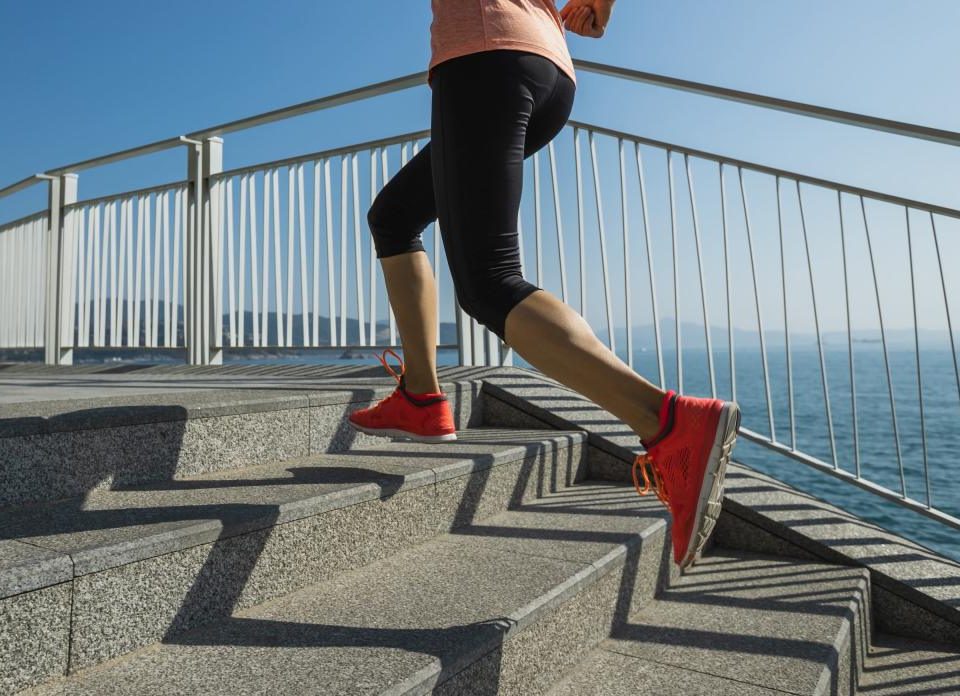 A person runs up stairs near the ocean.